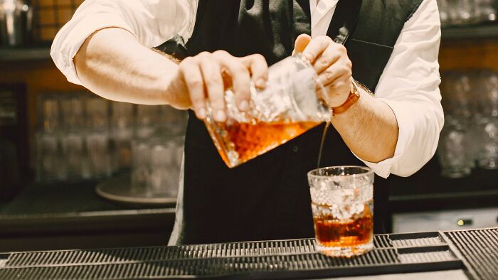 A bartender pouring a drink, a scene that could involve navigating 'Am I overreacting?' situations.