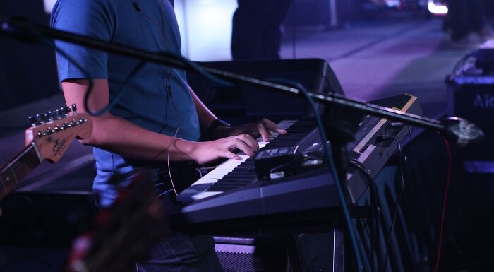 A musician playing a keyboard, showcasing popular music taste and music. The image captures the essence of live music.
