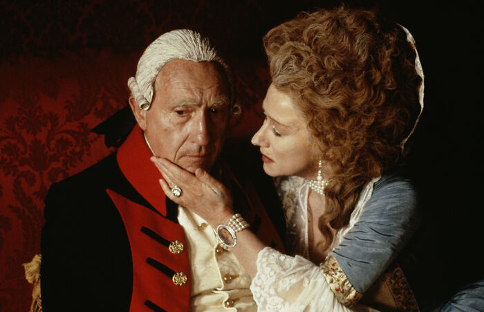 Two people in historical attire, a woman gently touching a man's face, illustrating interesting facts about history and costumes.