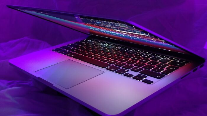 A laptop with a vibrant, colorful display in a purple-lit room. Explore stories about removing ex from family pictures.