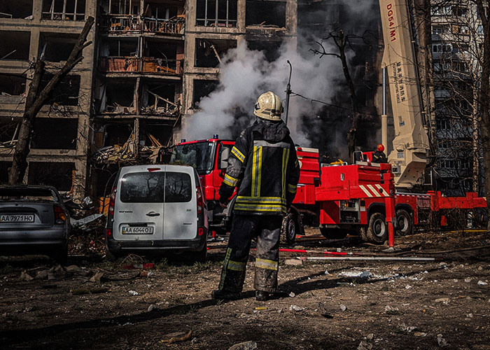 A firefighter stands before a burning building during the loneliest time, as people no longer look forward to birthdays.