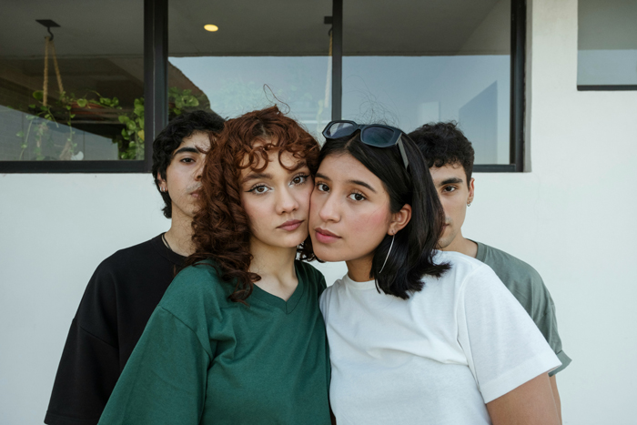 Two women with their heads together and two men in the background, hinting at mysterious stories of people.