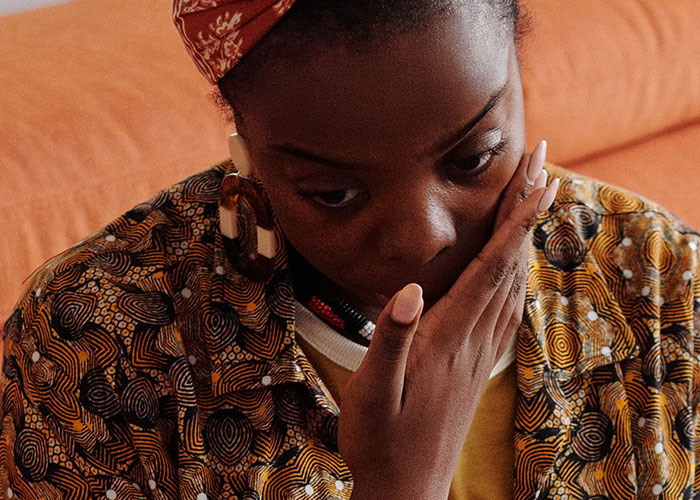 Woman looking concerned, hand covering mouth, reflecting on experiences of women leaving a man's home.