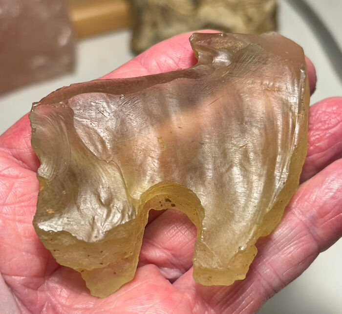 A hand holds a yellowish, translucent, irregularly shaped object, a mysterious discovery from ancient American history. A hand holds a yellowish, translucent, irregularly shaped object, a mysterious discovery from ancient American history.
