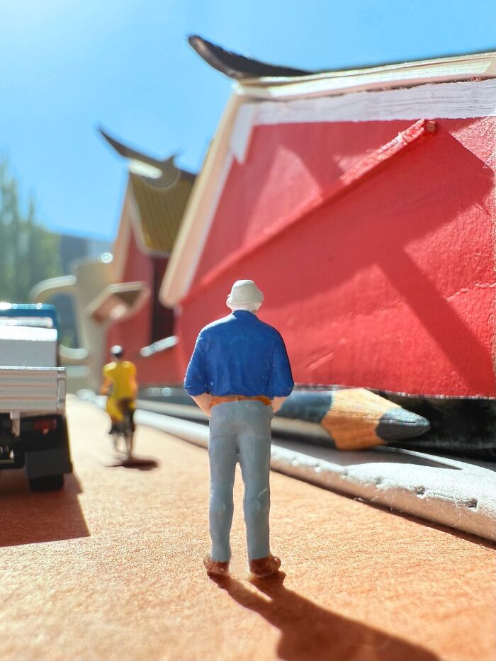 Artist Derrick Lin turns his office desk into intricate diorama sets, featuring a person walking past a red building.