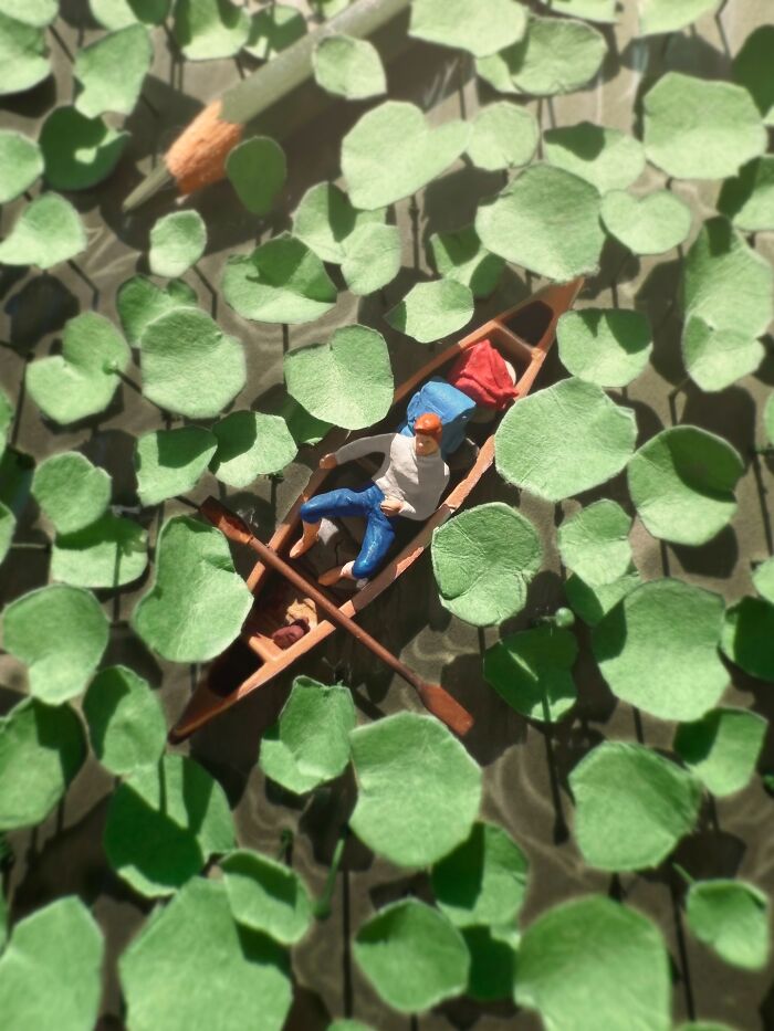 Artist Derrick Lin's diorama sets include a person paddling a small boat through a lily pad-filled pond.