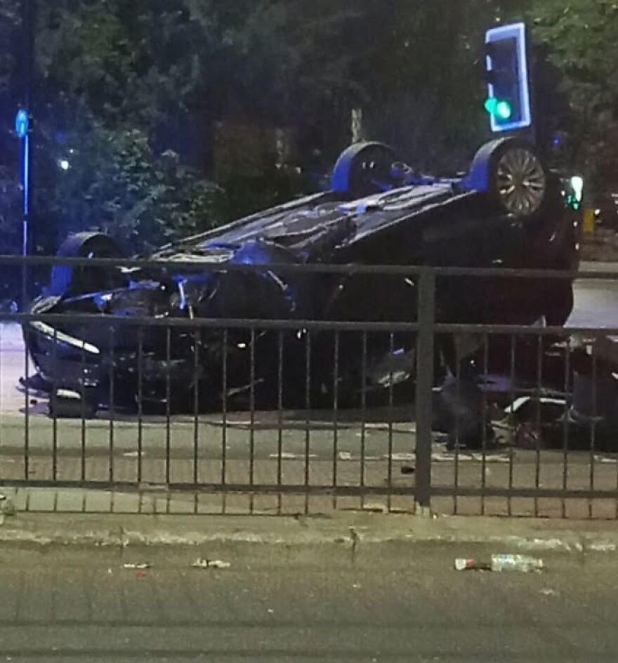 A black car flipped upside down on the road at night, showcasing a rough day behind the wheel for the driver.