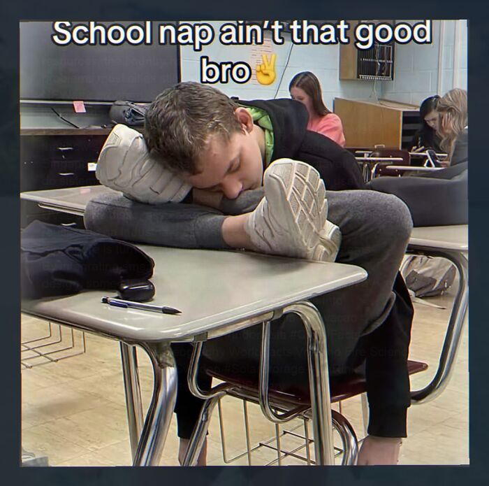 A student awkwardly sleeping on a school desk, head on arm and feet on the desk, highlighting weird memes about school.