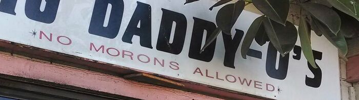 A sign that says No Morons Allowed, showing cultural decline into idiocy.