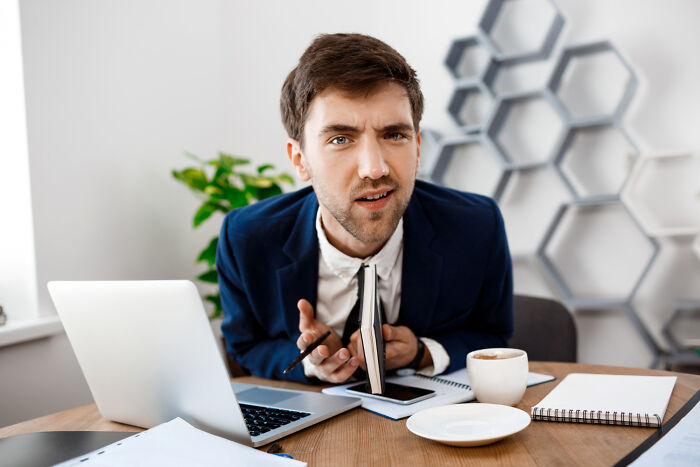A confused corporate worker sitting at his desk, reflecting on corporate buzzwords and practices.