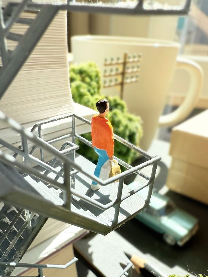 Artist Derrick Lin turns his office desk into intricate diorama sets, showing a person on a fire escape.