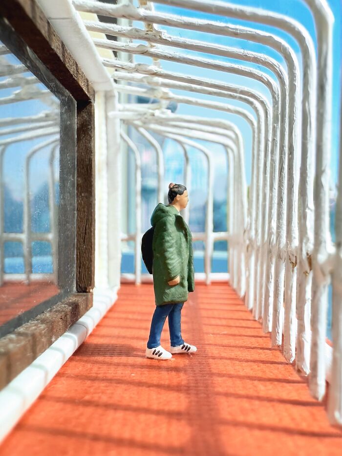 Artist Derrick Lin's intricate diorama set on his office desk shows a person on a walkway with a blue background.
