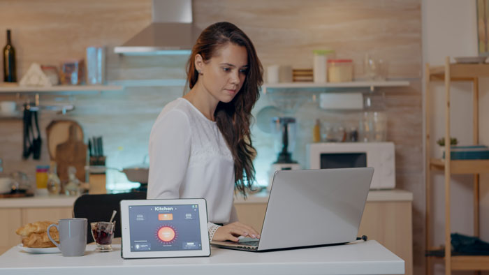A woman working on her laptop and tablet in a modern kitchen. The woman's boyfriend removed a business sign minutes earlier. A woman working on her laptop and tablet in a modern kitchen. The woman's boyfriend removed a business sign minutes earlier.