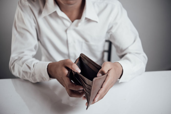 A man holds an empty wallet, symbolizing the fiancé's lack of savings and the bride-to-be's financial concerns. A man holds an empty wallet, symbolizing the fiancé's lack of savings and the bride-to-be's financial concerns.