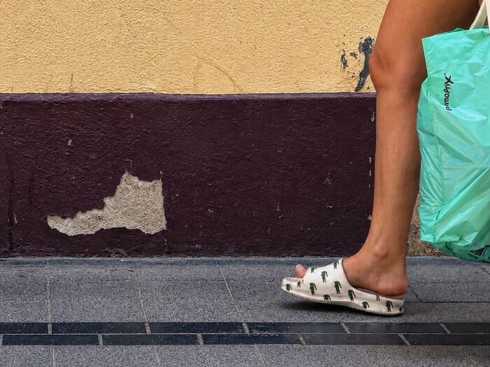 Perfectly timed coincidences in Barcelona: a person wearing a crocodile-print slide sandal walks past a peeling wall.