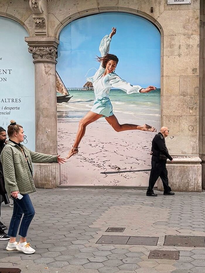 Photographer captures perfectly timed coincidence in Barcelona, showing a woman aligning with a jumping figure on a billboard.