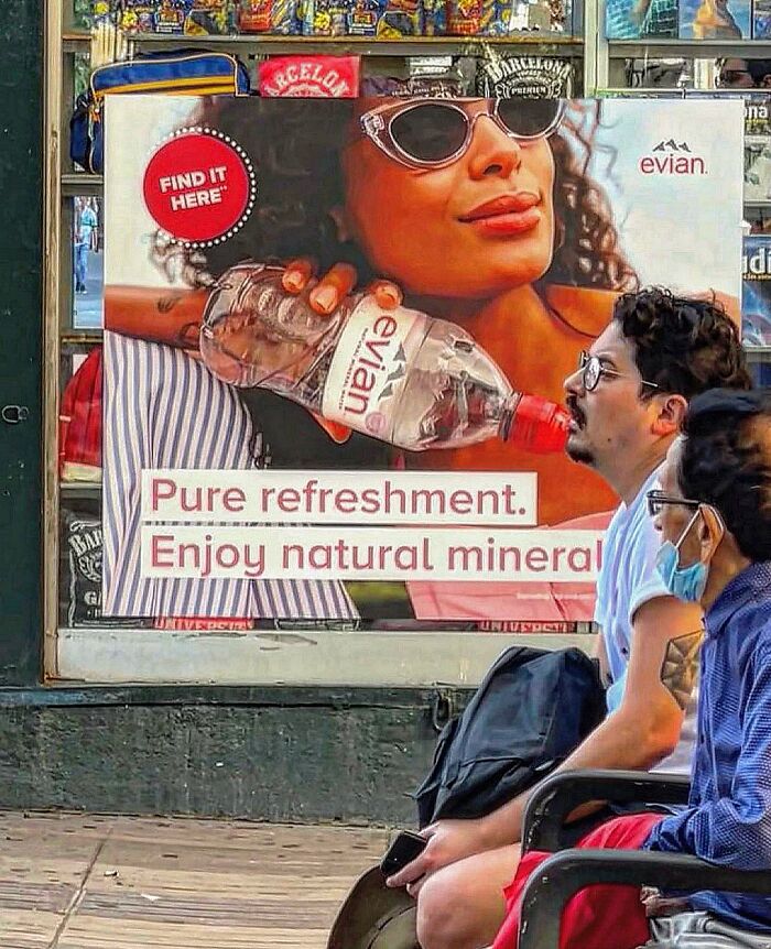 A perfectly timed coincidence in Barcelona shows a man appearing to drink from a bottle held by a woman in an advertisement.
