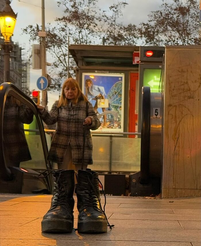 A perfectly timed coincidence in Barcelona shows a pair of large boots in the foreground, with a woman on an escalator behind them.