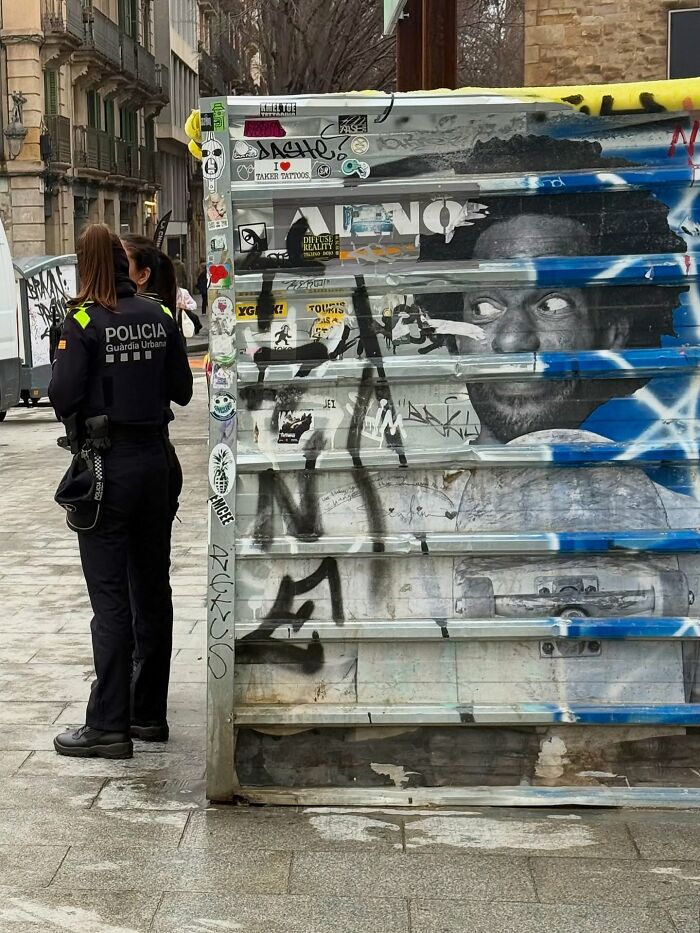 A perfectly timed coincidence in Barcelona shows a police officer standing next to graffiti that completes her face in an amusing way.