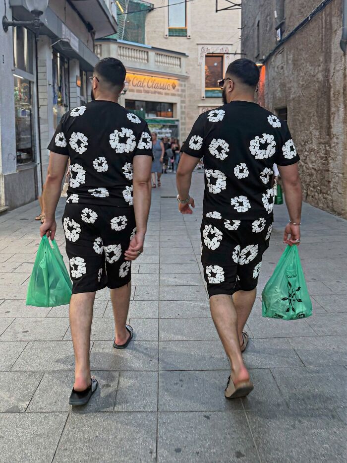 A photographer captures perfectly timed coincidences: two men walking in Barcelona, wearing identical black and white outfits.