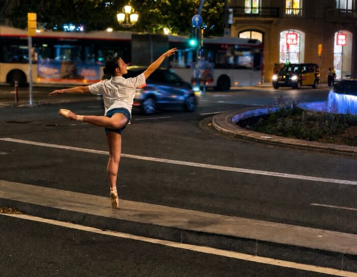 A photographer captures perfectly timed coincidences: a ballerina posing elegantly in Barcelona's busy street at night.