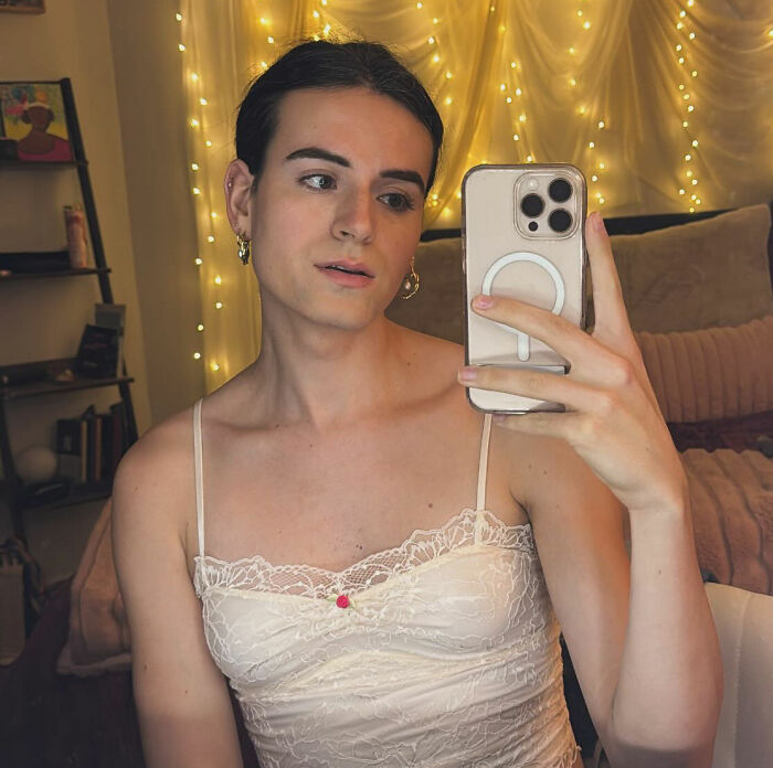 Trans influencer in a white lace top, taking a selfie, relevant to Lindsey Graham and hotel allegations.