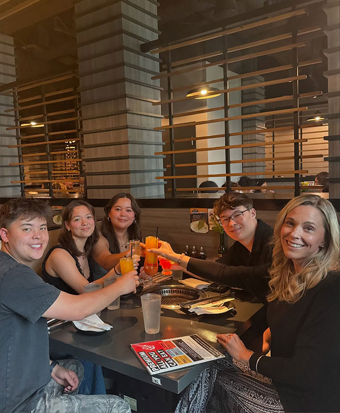 Collin Gosselin and a group of young adults, including a woman with blonde hair, clink glasses at a restaurant, amidst the public battle.