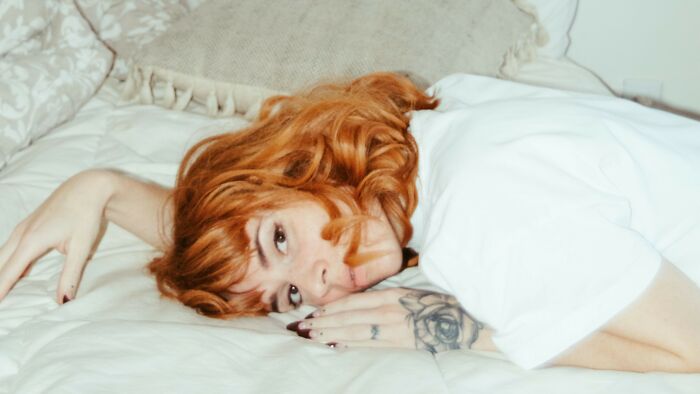 A young woman with red hair looking pensive, perhaps about not wearing her boyfriend's gift.