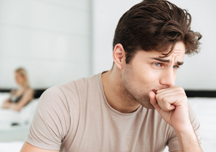 A man looking anxious, biting his nails, representing the stress and regret after having a baby.