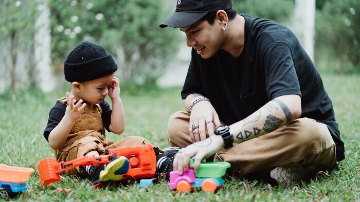 Father and child playing with toys on the grass, judging dating scenarios by their red, green, and beige flags.