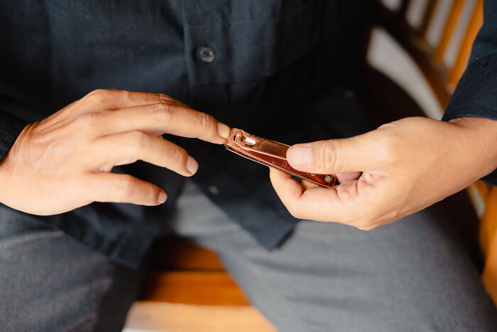 A man trimming his nails, a common task that could be done instead of attending regretful weddings.