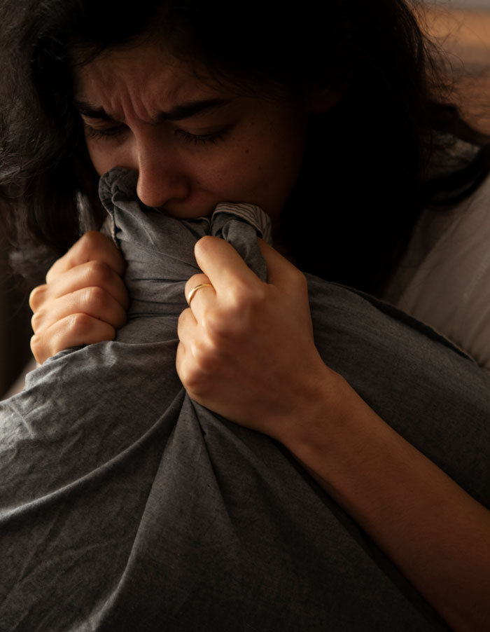 A woman crying into a pillow, contemplating a divorce lawyer due to her spouse's non-cheating behavior.