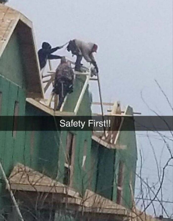 Two construction workers on a rooftop with the text Safety First, a humorous example of cultural decline.
