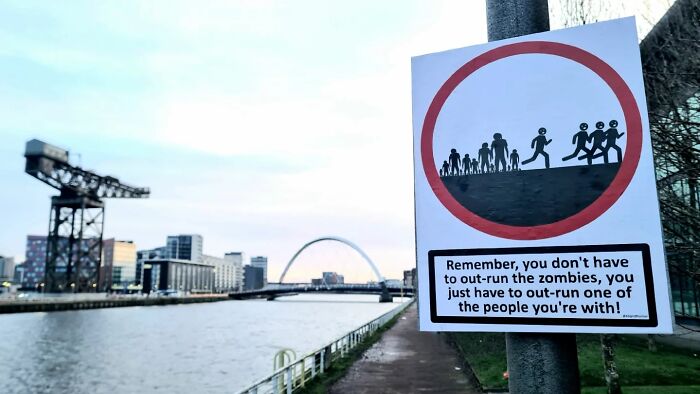 Absurd signs: A funny sign about outrunning zombies next to a river.