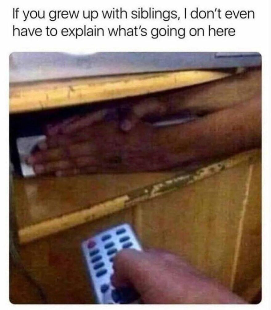A hand trying to grab a remote control under a desk, a situation '90s babies often faced with siblings.