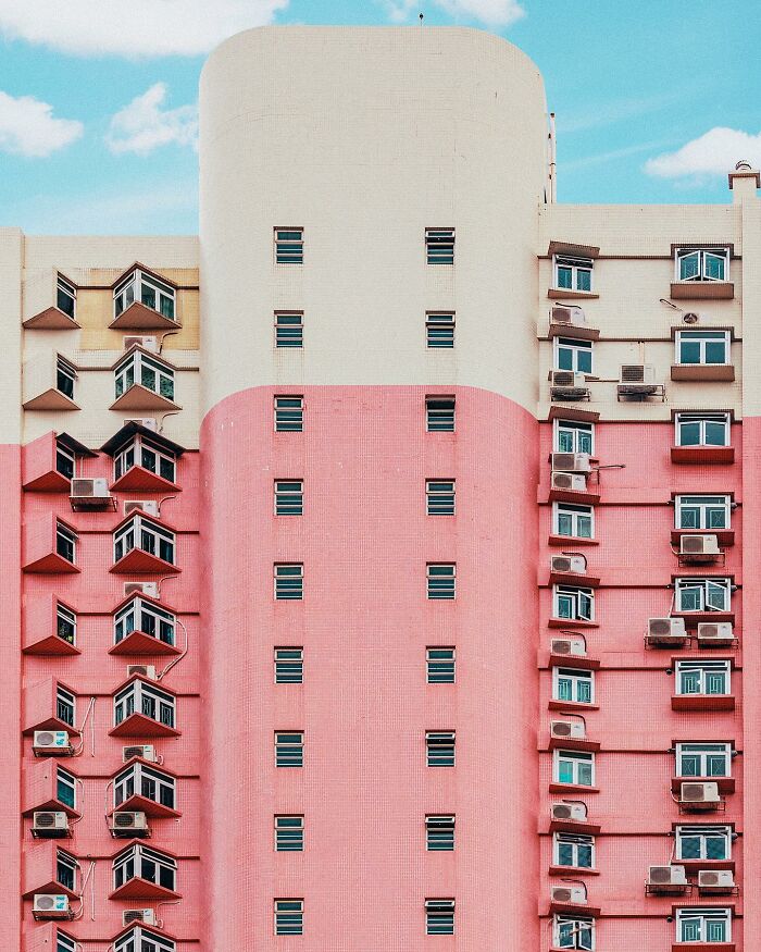 A photographer captures a perfectly composed image of a pink and white high-rise building with many windows and air conditioners.