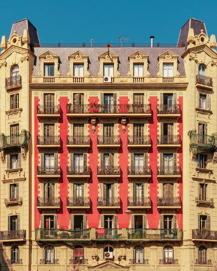 A photographer captures a perfectly composed image of a grand building with red accents and balconies, highlighting architectural locations.
