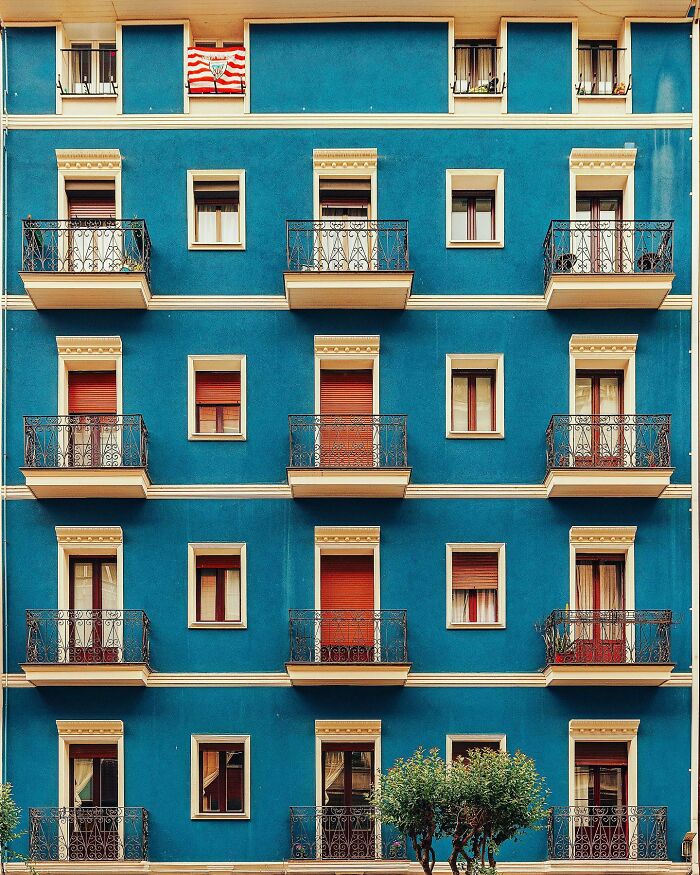 A photographer captures a perfectly composed image of a vibrant blue building with ornate balconies, highlighting architectural locations.
