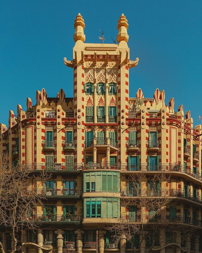 A uniquely designed architectural location building with ornate red and yellow patterns, intricate balconies, and green accents.