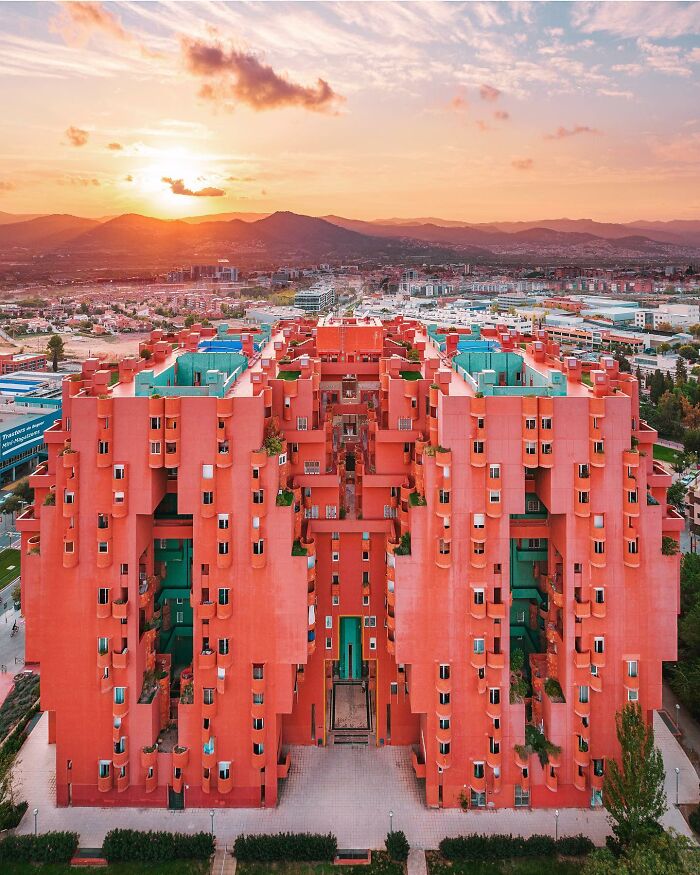 A photographer captures a perfectly composed image of a uniquely designed, vibrant architectural location against a sunset.