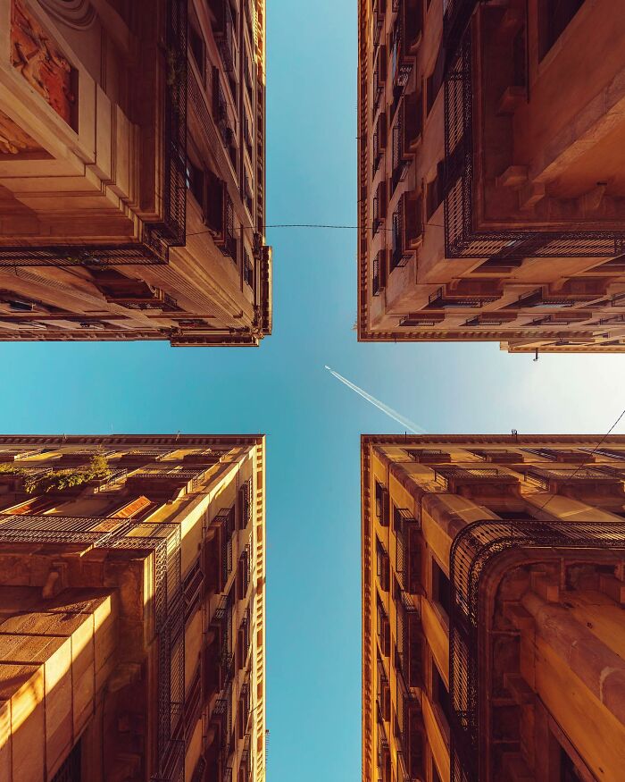 A photographer captures a worm's eye view of four historic buildings against a clear blue sky, highlighting architectural locations.