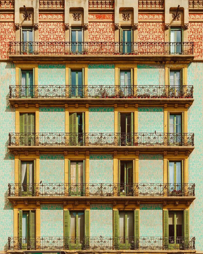An architectural location with ornate balconies and patterned teal and red walls under sunlight.