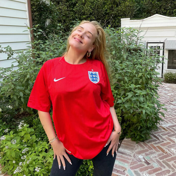 Adele smiling outdoors wearing a red England soccer jersey in public Adele smiling outdoors wearing a red England soccer jersey in public