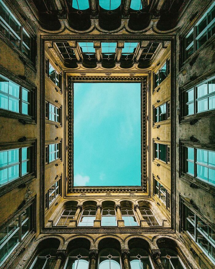 A photographer captures a perfectly composed image looking up at an ornate building, revealing the sky above, emphasizing architectural locations.