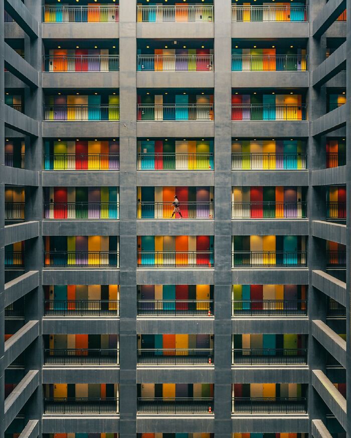 A photographer captures a perfectly composed image of a building's interior, featuring rows of colorful doors, showcasing architectural locations.