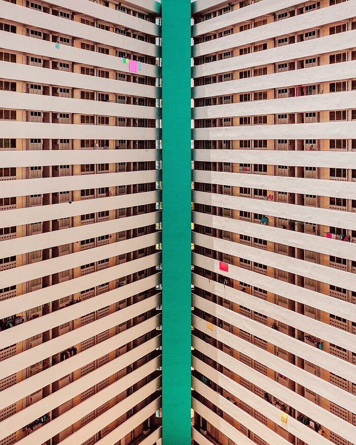 An abstract view of a tall architectural location building with a bright green central column separating rows of balconies.