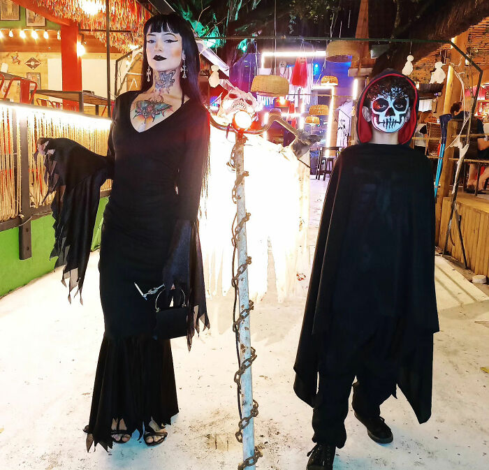 Goth influencer and a person in a skeleton costume posing together outdoors at night. Goth influencer and a person in a skeleton costume posing together outdoors at night.