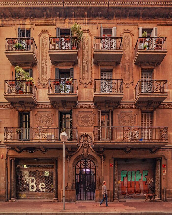 Detailed street-level view of an architectural location with ornate balconies and a pedestrian walking by, highlighting architectural locations.