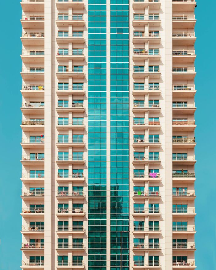 A photographer captures a tall, white residential building with multiple balconies, a must-see architectural location.