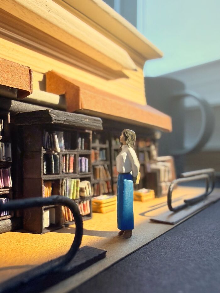 Artist Derrick Lin creates intricate diorama sets of a woman browsing books in a library.
